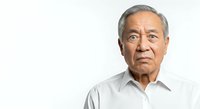 Senior Asian man with gray hair wearing light gray button-up shirt, looking directly at camera with neutral expression against white background for corporate or professional use.