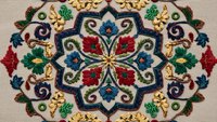 Ornate embroidered mandala with colorful floral motifs and gold accents on beige fabric background for traditional textile and decorative arts projects.
