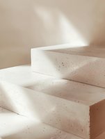 Minimalist concrete steps with natural sunlight casting soft shadows, creating abstract geometric shapes in neutral beige tones for modern interior design.