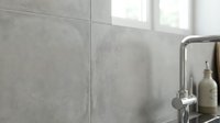 Modern minimalist bathroom interior with gray concrete-style tiles and chrome fixtures creating clean contemporary design for home renovation projects.