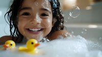 Young Asian girl with wet curly hair smiling brightly during bath time with yellow rubber ducks and soap bubbles floating around in playful bathroom scene.