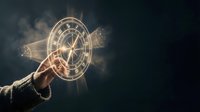 Hand pointing at glowing zodiac wheel with mystical smoke effects on dark background for astrology and fortune telling concepts.