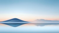 Minimalist mountain landscape reflected in calm water at dawn with soft pastel colors and misty atmosphere creating serene nature scenery.