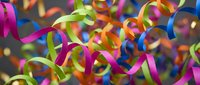 Colorful party ribbons and streamers in vibrant pink, green, blue and yellow creating festive celebration background for holidays and special events.