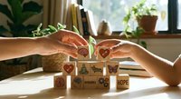 Hands protecting wooden blocks with environmental symbols and green plant sprout representing sustainability, eco-friendly business growth and nature conservation.