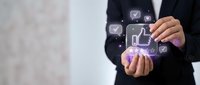 Businessman in dark suit holding glowing digital social media icons including thumbs up and chat symbols, representing online engagement and digital marketing strategy.
