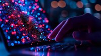 Fingers typing on laptop keyboard with magical glowing particles and bokeh lights in blue and pink colors creating dreamy night atmosphere for technology concept.