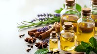 Natural essential oils in glass bottles with fresh herbs, lavender, mint, cinnamon sticks and star anise for aromatherapy and wellness treatments.