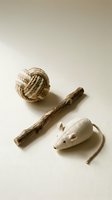 Natural cat toys set with rope ball, wooden stick, and fabric mouse on beige background, eco-friendly pet accessories for cats.