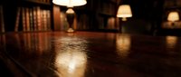Empty wooden library or study room with polished floor reflecting warm pendant lighting and bookshelves, suitable for interior design and architectural projects.
