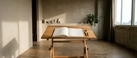 Minimalist wooden desk with open book in modern home office interior with natural lighting and concrete walls for workspace design.