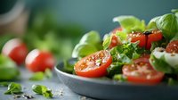 Fresh caprese salad with cherry tomatoes, mozzarella pearls, and basil leaves garnished with herbs and seasonings on dark plate, macro food photography.