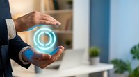 Businessman hands protecting glowing blue circular hologram in modern office environment representing data security and digital protection concepts.
