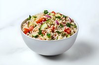 Fresh tabbouleh salad with bulgur wheat, diced tomatoes, cucumbers, red onion and parsley in white ceramic bowl on light background. Perfect for Mediterranean cuisine.