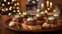 Grilled beef tenderloin medallions with herb cream on toasted bread slices served on wooden platter during festive holiday dinner celebration.