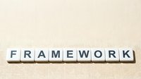 Wooden letter tiles spelling FRAMEWORK on neutral beige background for business strategy and organizational structure concepts.