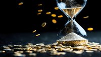 Hourglass with golden sand measuring time on dark background with scattered coins, symbolizing time value and financial decisions in business concept.