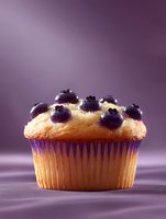 Fresh blueberry muffin with golden top and juicy berries on purple gradient background for bakery menu and dessert advertising.