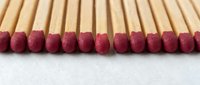 Row of wooden matches with red sulfur tips arranged in perfect line on white background for fire safety and lighting concepts.