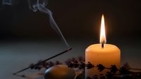 Burning candle with smoke and coffee beans creating warm atmospheric lighting for relaxation and aromatherapy concepts.