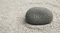 Smooth gray stone with strain text engraved on surface, resting on sand background. Concept for stress relief, mental health awareness, and wellness messaging.