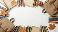 School supplies frame with colorful pencils, notebooks and autumn leaves on white background. Back to school concept with copy space for text.