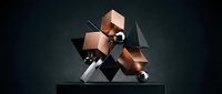 Copper and black geometric shapes with metallic spheres arranged on dark platform, representing modern abstract design and contemporary art composition.