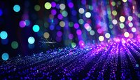 Glowing purple and blue bokeh lights create magical atmosphere with sparkling rays spreading across dark background, festive holiday illumination effect.