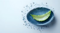 Fresh aloe vera leaf slice with water drops on blue stone background, natural organic skincare and wellness concept for spa and beauty.