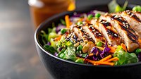 Grilled chicken Asian salad bowl with fresh vegetables, sesame seeds and teriyaki glaze. Colorful healthy meal with purple cabbage, carrots, and green lettuce.