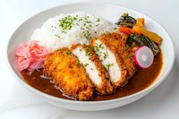 Crispy breaded pork cutlet served with steamed rice, curry sauce, pickled vegetables and garnished with fresh herbs on white ceramic plate. Japanese cuisine.