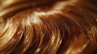 Flowing waves of rich chocolate brown hair with golden highlights create dynamic movement and texture, capturing light in a luxurious, abstract macro composition.