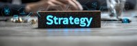 Glowing blue strategy text on dark nameplate against blurred business background with digital icons and technology elements creates modern corporate atmosphere.