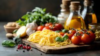 Fresh raw pasta with cherry tomatoes, basil leaves, garlic, and cooking ingredients on rustic wooden board against dark background. Mediterranean cuisine preparation.