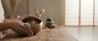 Hands holding wooden bowl in serene spa setting with zen stones and natural lighting for wellness meditation and mindfulness practices.