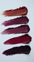 Textured swatches of burgundy and purple lipstick smears showing gradient color palette from coral red to deep plum on white background for makeup and cosmetics design.