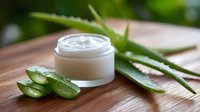 Fresh aloe vera leaves and white cosmetic cream jar on wooden background, natural skincare and beauty treatment concept for spa and wellness.