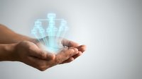 Cupped hands holding glowing digital healthcare icons with cross symbols representing telemedicine and medical technology innovation.