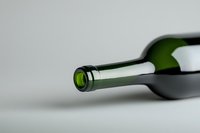 Empty green wine bottle lying on gray background with focus on bottle neck and opening, minimalist composition for beverage and alcohol concepts.