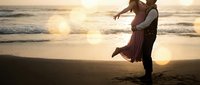 Romantic couple dancing on beach at sunset with golden light reflecting on ocean waves creating intimate moment for wedding or anniversary celebration.