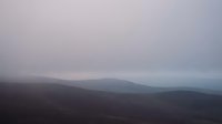 Misty mountain landscape with rolling hills shrouded in fog and overcast sky creating moody atmospheric scenery for nature backgrounds and travel content.
