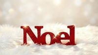 Red glittery Noel sign on white fluffy fur with soft bokeh background, festive Christmas holiday decoration for seasonal greeting cards and banners.