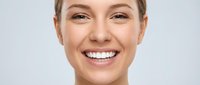 Happy young Caucasian woman with bright white smile and natural makeup showing perfect teeth in close-up portrait for dental care and beauty concepts.