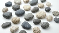 Collection of smooth river stones and pebbles in natural gray, beige and speckled colors isolated on white background for spa, zen meditation and decoration.