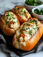 Freshly baked chicken and cheese submarine sandwiches garnished with chopped parsley on dark stone board, served with herbs in bowls. Melted mozzarella topping.