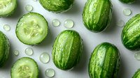 Fresh sliced and whole mini cucumbers with water drops on light gray background, top view. Natural organic vegetables for healthy eating.