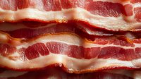 Raw bacon strips with marbled fat and lean meat showing natural texture and color variations for culinary and food photography projects.