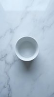 Empty white ceramic bowl on marble surface, overhead view for kitchen, dining, and product styling projects.