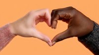 Diverse hands forming heart shape against orange background, representing unity, love and racial harmony in modern society. Powerful message of acceptance.