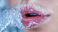 Close up of sensual red lips covered in frost and ice crystals, creating dramatic contrast between warm and cold elements for beauty and cosmetic concepts.